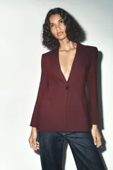 Blazer marrón de corte entallado, con cuello solapa, manga larga, bolsillos delanteros con solapa y cierre frontal con un botón.