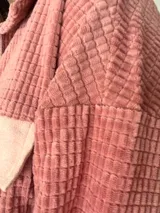 Sobrecamisa de pana texturada color rosa con detalles en tono más claro, corte oversize, bolsillos frontales aplicados y cierre frontal con botones.