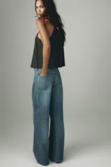 Jeans de tiro alto con pierna ancha y largo completo. Confeccionados en tejido rígido con cinco bolsillos, cintura con trabillas, detalle de costuras torcidas y cierre con cremallera y botón metálico.