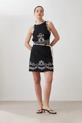 Minifalda negra de tiro alto con bordado blanco en el ruedo y cinturón de soga.