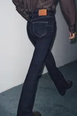 Pantalón de jean azul oscuro, de tiro bajo, corte slim fit y bootcut. Con cinco bolsillos y cierre frontal con cremallera y botón.