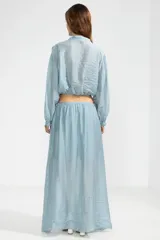 Blusa corta celeste en tejido arrugado liviano, con cuello mao, botones al frente y mangas abullonadas. Terminada con ruedo elastizado.