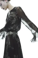 Vestido largo negro con estampado paisley, escote en pico, mangas largas acampanadas con volantes y cintura elastizada con cordón ajustable.