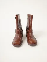 Botas cortas de cuero marrón con textura, hebillas ajustables, apliques circulares y punta cuadrada.