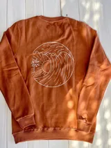 Buzo color ladrillo de corte estándar con cuello redondo y puños y cintura acanalados. Estampado en la espalda con diseño de una ola, un sol y una palmera.