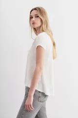 Remera de mangas cortas color crudo, confeccionada en lino y viscosa. Presenta bordados a tono con apliques de lentejuelas, canutillos y mostacillas en la parte superior.
