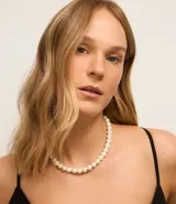 Collar corto de perlas blancas con cierre metálico dorado.