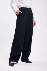 Pantalón negro de vestir, de corte palazzo y tiro alto, con bolsillos laterales.