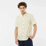 Camisa de lino color amarillo claro, de corte recto, con cuello mao, manga corta con dobladillo y cierre frontal con botones.