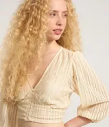 Blusa corta de encaje guipir de algodón con escote en V, botones frontales y manga larga abullonada con puño elástico.