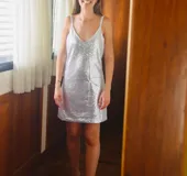 Vestido corto plateado con lentejuelas, escote en V y tirantes finos.