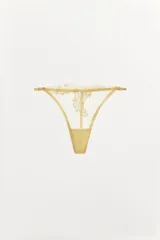 Tanga color dorado semitransparente con detalle de encaje floral en el frente. Cintura elástica fina y ajustable.