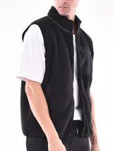 Chaleco negro de polar con cierre frontal y cuello alto. Tiene un bolsillo con cierre en el pecho y bolsillos laterales.