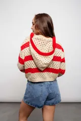 Buzo de tejido de punto calado color beige con rayas horizontales rojas y capucha.