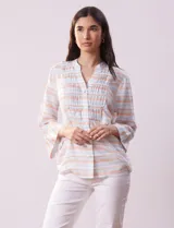 Blusa estampada a rayas horizontales en tonos celeste, blanco y naranja, con cuello mao, escote en V y abertura con botones. Delantero con punto smock. Manga ¾ con terminación amplia.