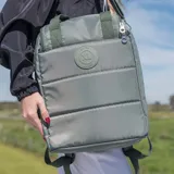Bolso matero verde de poliéster con diseño acolchado. Tiene acceso con cierre doble, múltiples bolsillos internos y externos, compartimentos para notebook y matero, asas fijas, correa regulable y herrajes plateados.