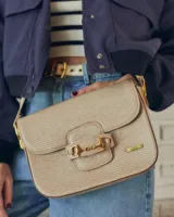 Bandolera color beige con textura símil reptil, cierre con broche metálico dorado y correa larga regulable.