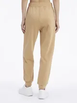 Pantalón de jogging color beige, de corte relajado, con cintura y tobillos elásticos, bolsillos laterales y logo pequeño en el lateral.