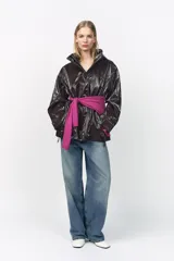 Parka marrón brillante con cuello alto y capucha oculta con cremallera metálica. Manga larga ajustable con cinta y botones a presión. Bolsillos delanteros con cremallera metálica. Cintura ajustable. Cierre frontal con cremallera y botones a presión.