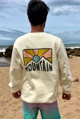 Buzo color crema de corte clásico con estampa en la espalda con un paisaje de montaña y la palabra "Mountain" en tipografía sans-serif.