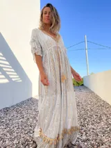Vestido túnica largo de color celeste con bordados dorados y detalles de encaje en el escote y ruedo.