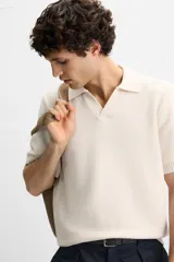 Polo color crema de punto con cuello solapa y abertura frontal en V.
