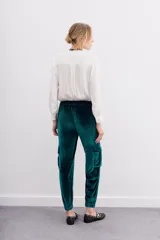 Pantalón babucha verde esmeralda de terciopelo con elástico en la botamanga, bolsillos plaqué en el frente con remaches metálicos y bolsillos cargo en las piernas.