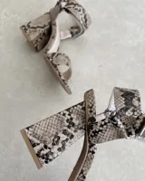 Sandalias plateadas con tira delantera, tobillera con hebilla y taco geométrico.