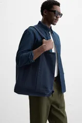 Bolso tipo shopper color azul marino, fabricado en tejido de algodón. Tiene doble asa de mano y un bolsillo plano en el interior.