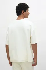 Remera color crema de punto de algodón pesado, con cuello redondo ribeteado, hombros caídos, bajo recto y corte oversized.