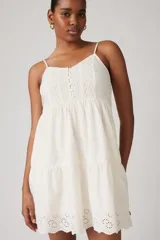 Vestido corto blanco con bordado inglés, breteles finos y falda escalonada.