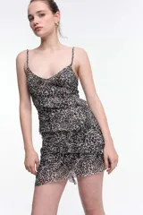 Vestido corto negro con lunares blancos, breteles finos y volados horizontales.