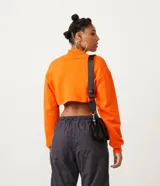 Buzo cropped blanco de algodón con cuello alto y puños acanalados.