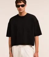 Remera negra de algodón con poliéster y elastano, corte oversized, cuello redondo, manga corta y tejido acanalado.