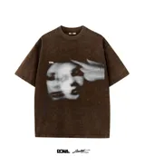 Remera marrón con efecto lavado, cuello redondo y manga corta. Estampa frontal con imagen en blanco y negro de rostro difuminado y mano apuntando.