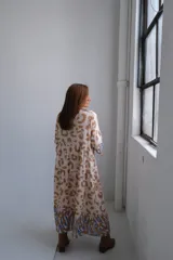 Vestido midi de corte amplio, color beige con estampado abstracto en tonos marrones. Mangas tres cuartos con detalle de volados en puños con estampado a rayas celestes y marrones.