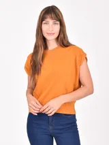 Remera de manga corta, color naranja quemado, con cuello redondo y mangas caídas que simulan un efecto de hombro doblado.