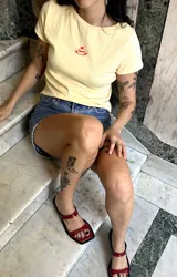 Remera color amarillo pastel, estilo baby tee, de algodón con cuello redondo y estampado pequeño de un postre con cereza.