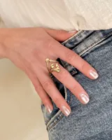 Anillo dorado de acero con diseño abstracto de hojas.