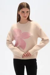 Sweater color beige con estampado de flor rosa, de corte ancho y cuello redondo.