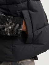 Chaleco acolchado negro sin mangas con cuello alto y cierre de cremallera.