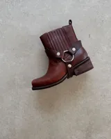 Bota de cuero color marrón con caña alta, hebillas y arnés.