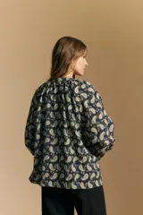 Camisa de manga larga con cuello mao y estampado paisley en tonos beige, marrón y azul sobre fondo claro. Presenta un calce holgado y puños ajustados.