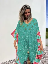 Túnica corta verde con estampado de flores rojas y detalles bordados. Mangas anchas con terminación en volados con estampado floral en tonos rosa y celeste.