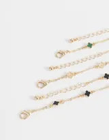 Set de tres pulseras doradas con dijes de flores de metal y resina.