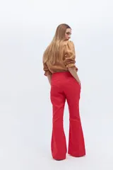 Conjunto de blazer y pantalón acampanado color rojo. El blazer es de corte clásico con solapas y un botón, y tiene volados en las mangas. El pantalón es de tiro alto y pierna acampanada.