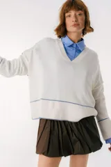 Sweater beige y azul con cuello en V y ribete bordeaux.