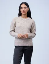 Buzo de tejido melange color beige con puntos oscuros, cuello redondo y manga larga.