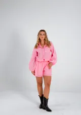 Conjunto rosa de lino, compuesto por una camisa de manga larga con corte holgado y un short de tiro alto.