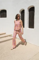 Top sin mangas con estampado floral en tonos rosa y naranja, con cuello redondo y espalda descubierta atada con tres lazos.